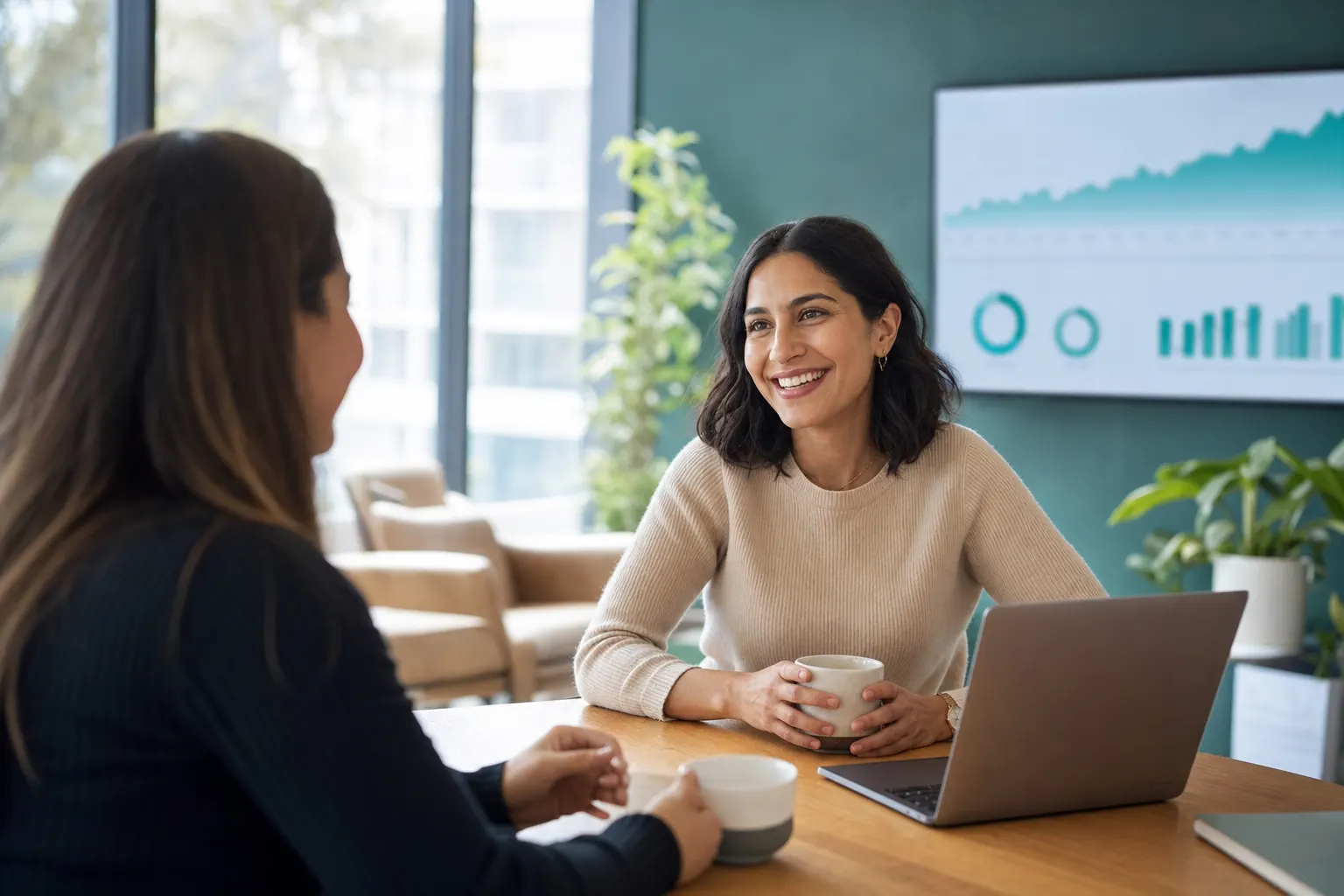 A customer success manager meeting a happy client beside a screen showing account growth metrics.